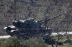 A Turkish soldier stands on top of a tank near the Turkish-[...].jpg